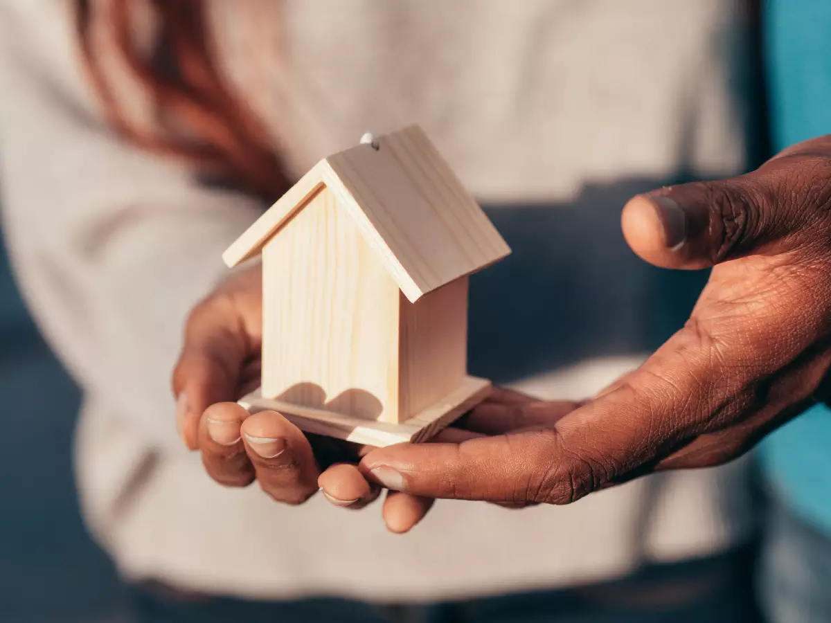 TVA logement neuf - Un couple qui tient dans ses mains une maison miniature en bois