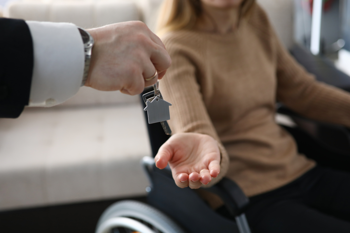 Normes PMR logement neuf – Une jeune femme en fauteuil roulant récupère les clés de son logement neuf