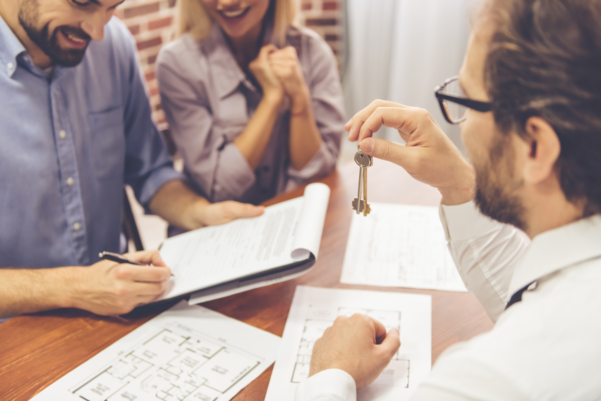 Location à Nantes – Jeune couple signant son contrat de location et agent immobilier leur tendant les clés