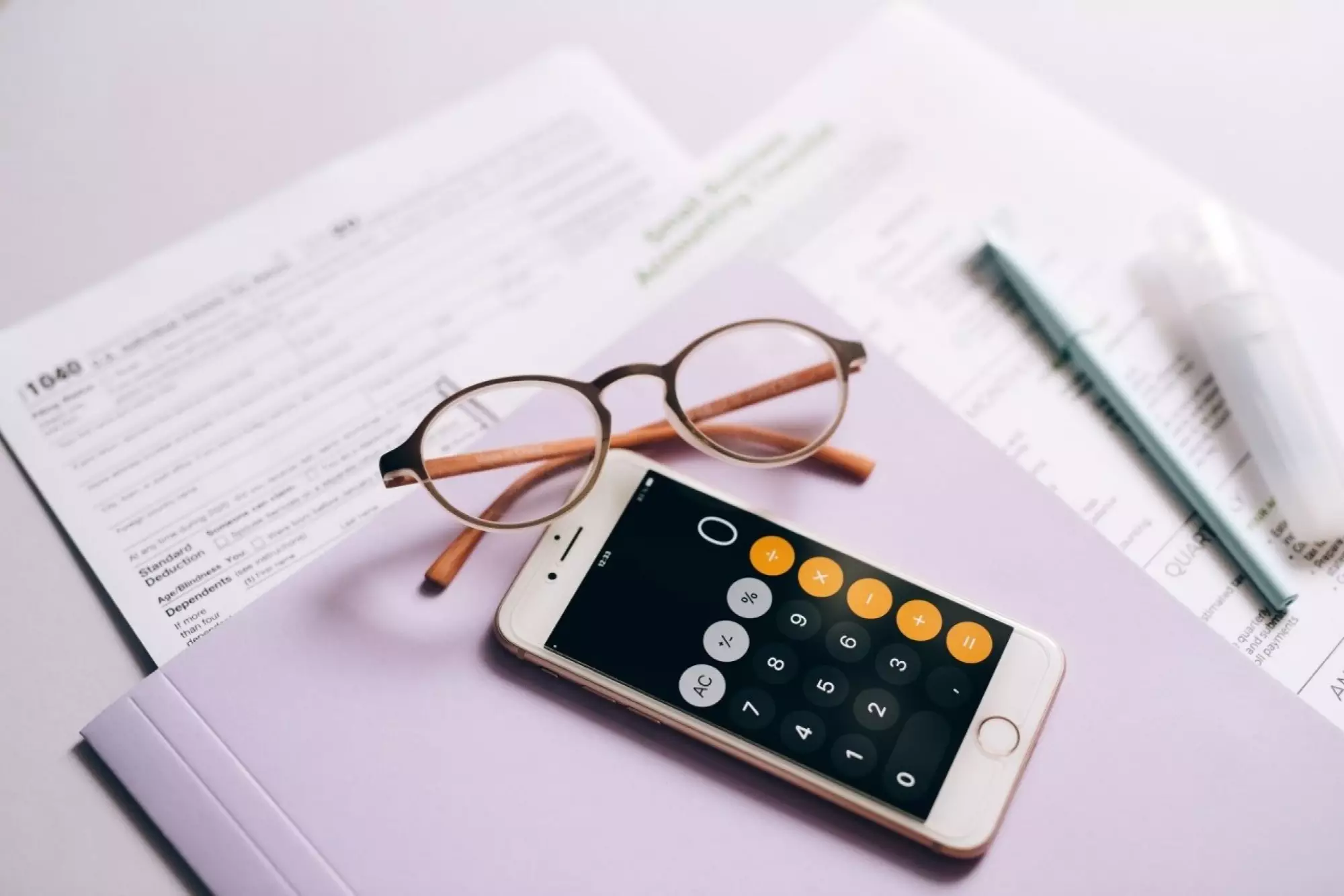 Calculatrice et lunettes posées sur un bureau avec des fiches de comptabilité