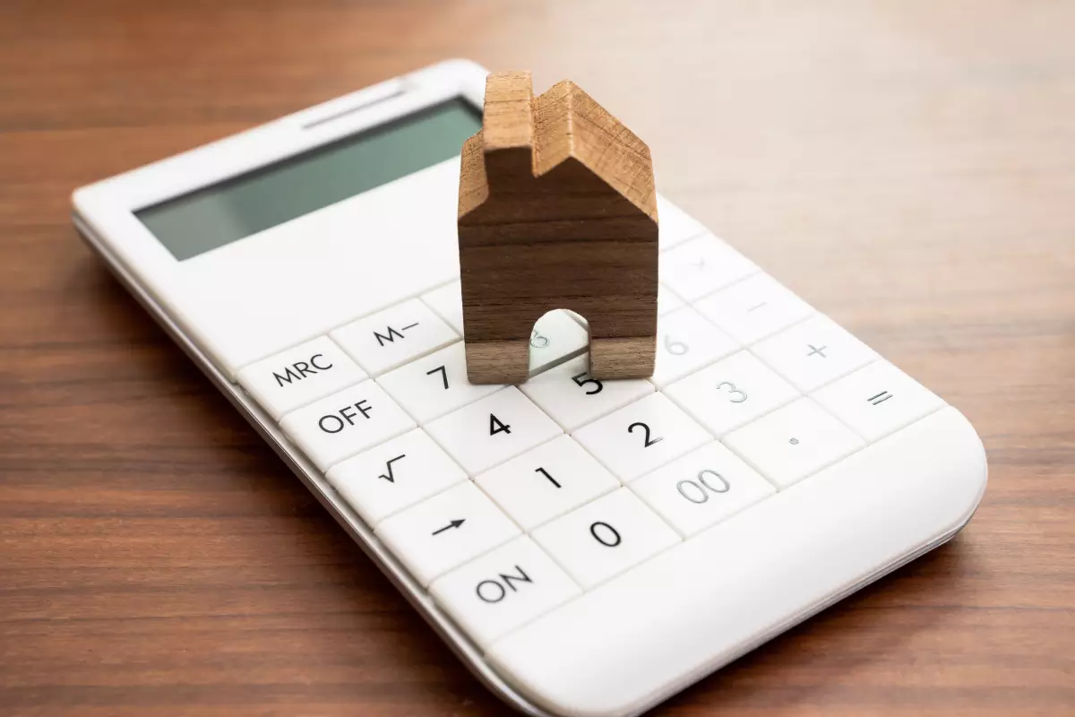 Revente appartement neuf avant 5 ans – Maisonnette en bois posée sur une calculatrice
