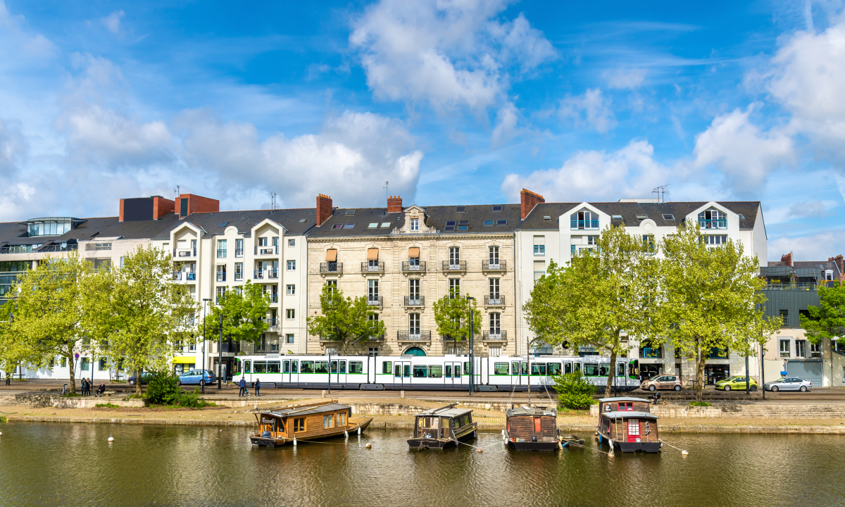Marché immobilier Loire Atlantique – Des immeubles et le tram en bord de Loire sur laquelle stationnent des péniches