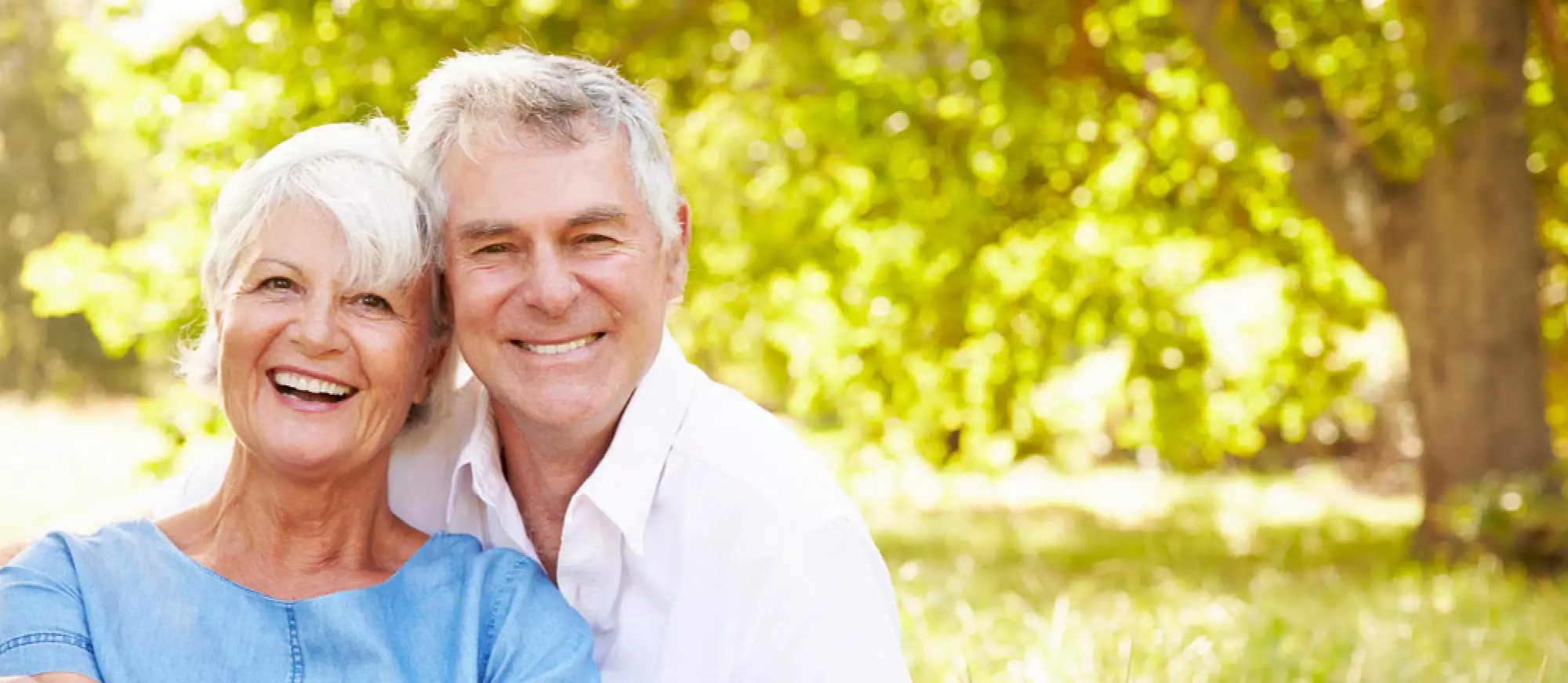 Un couple de séniors assis dans l’herbe en train de sourire