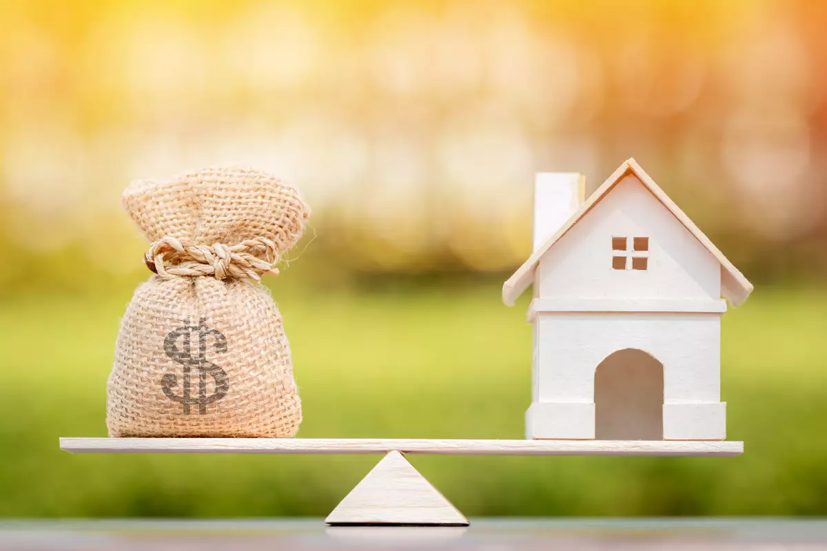 une balance avec un sac d’argent et un bien immobilier