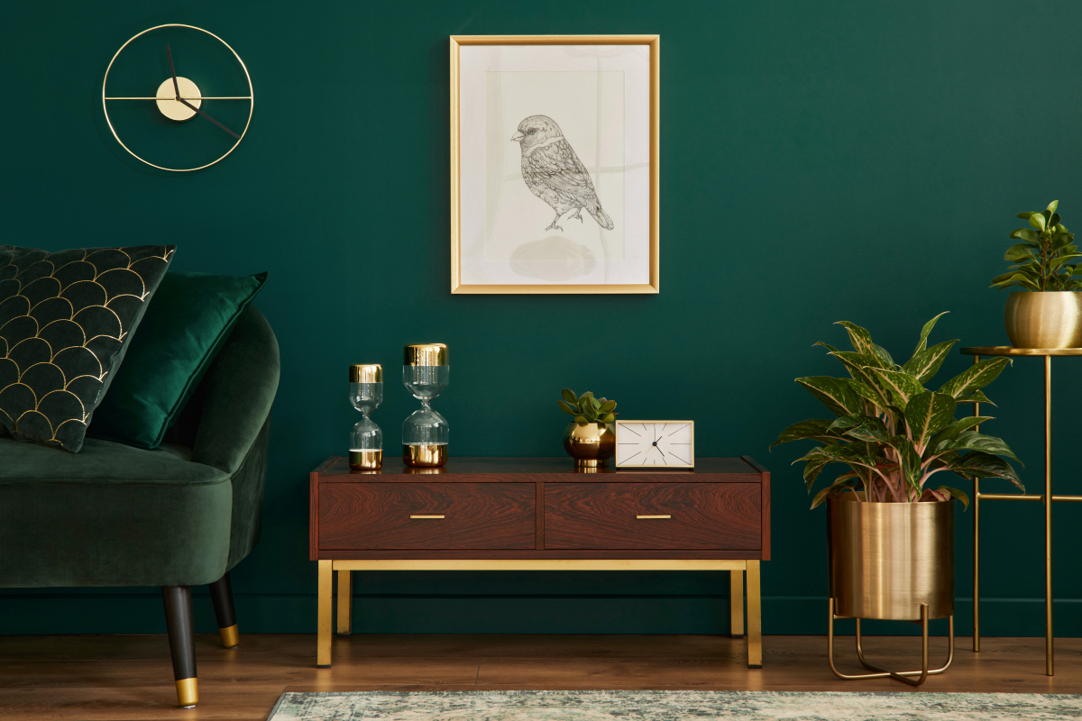 Donner du cachet à un appartement neuf – Une pièce au mur vert sapin décorée d’objets dorés