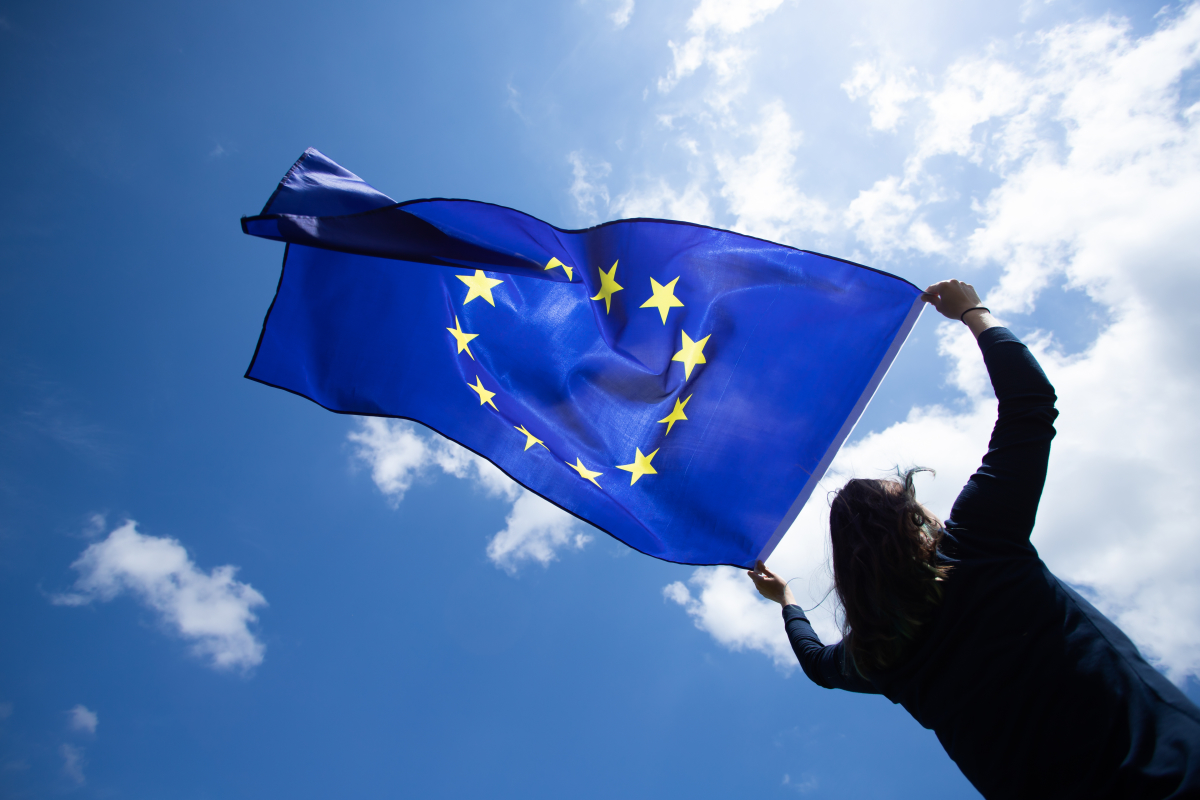Neutralité climatique – Jeune femme tenant un drapeau de l’Union Européenne au vent