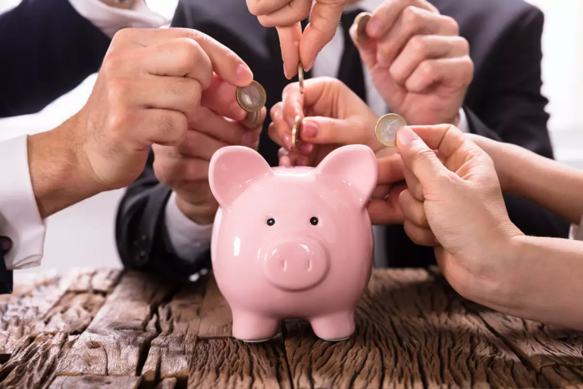 Qu'est-ce que les charges de copropriété ? des mains mettent des pièces de monnaie dans une tirelire
