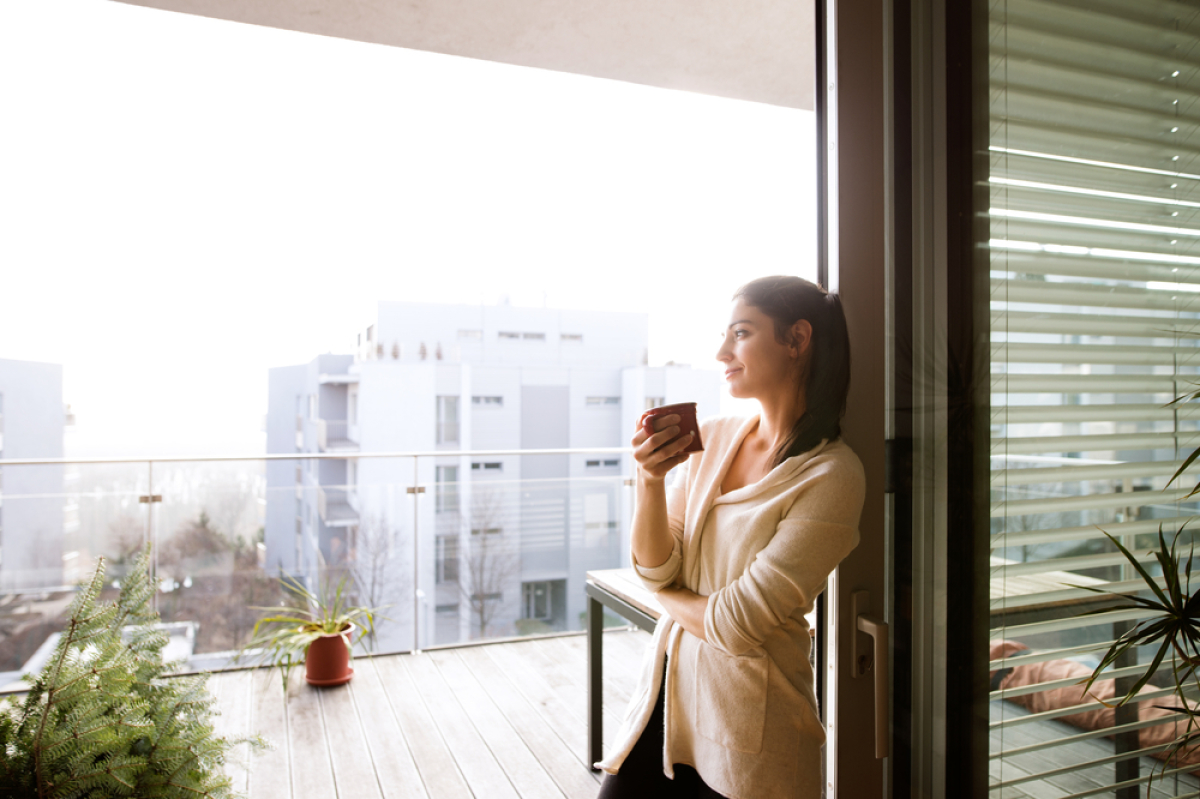 Assurance prêt immobilier 2023 - Une jeune femme sereine sur le balcon de son appartement