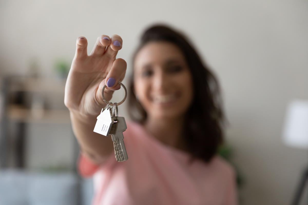  Gestion locative appartement neuf – Une jeune femme souriante qui tient un trousseau de clés 