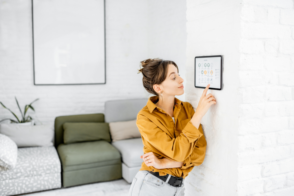  Domotique et appartement neuf – Une jeune femme en train de contrôler les équipements de son appartement depuis une tablette 