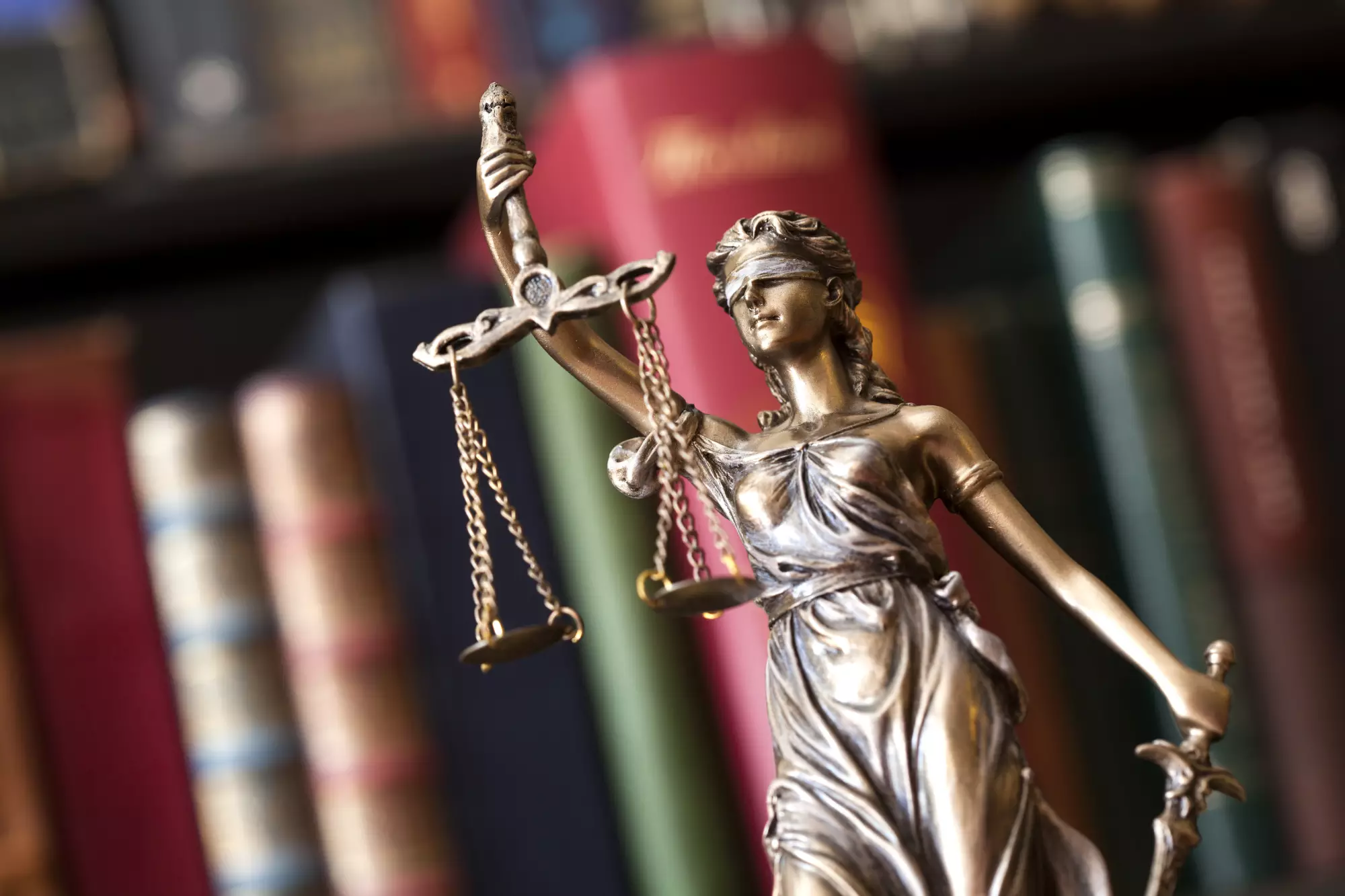 Une statue représentant la justice devant des livres de droit