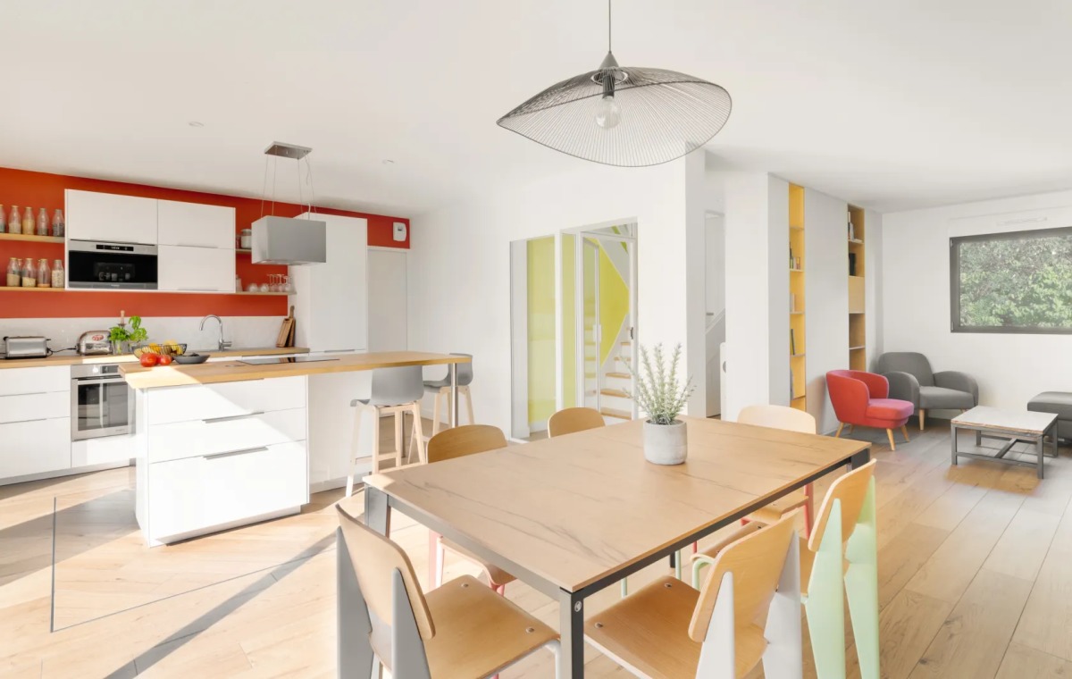 Une cuisine moderne et colorée ouverte sur une salle à manger lumineuse d'une maison à Nantes
