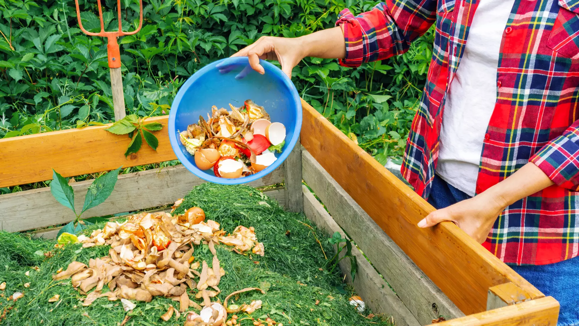 Une personne ajoute des épluchures de légumes au compost