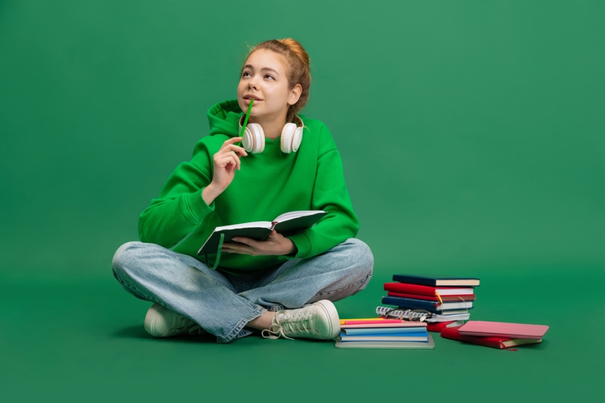 Bail étudiant Nantes – une étudiante en train de réfléchir à côté d’une pile de livres