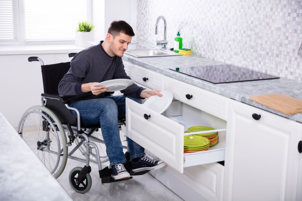 un homme en fauteuil roulant range sa vaisselle