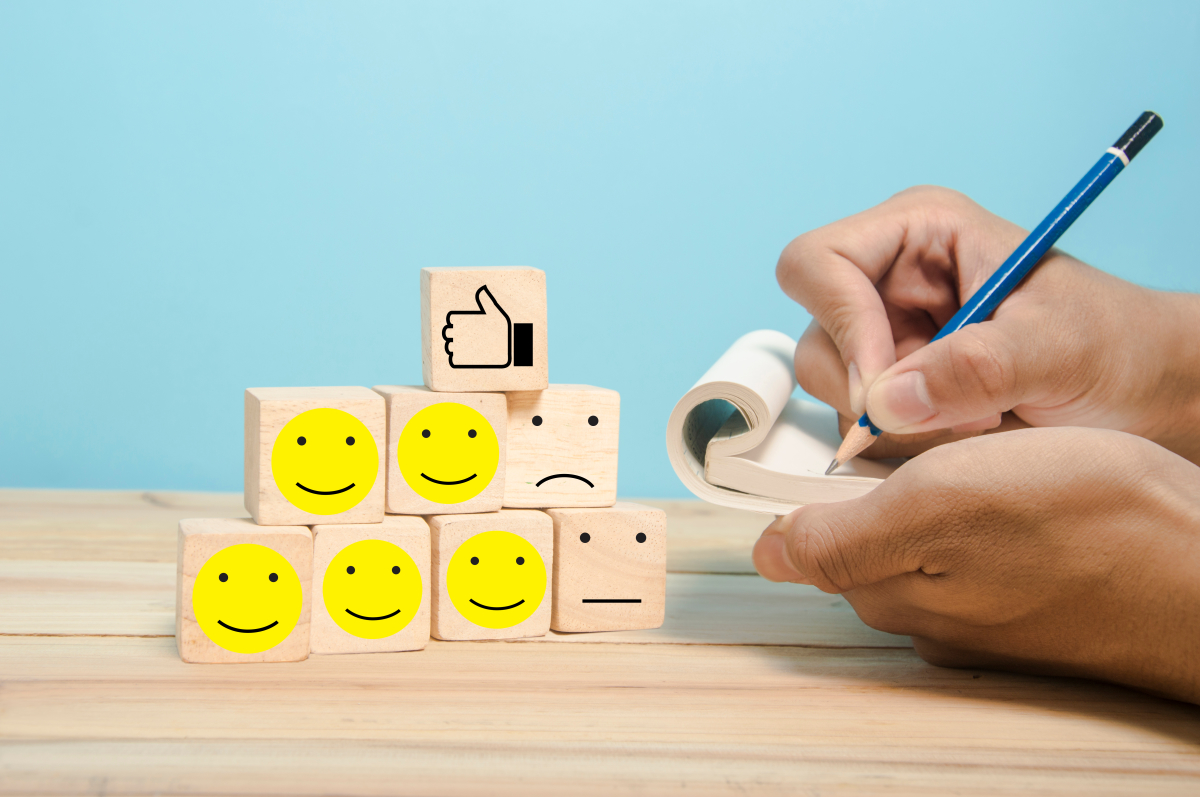 des cubes de bois avec des smileys contents et pas contents avec des mains qui prennent des notes