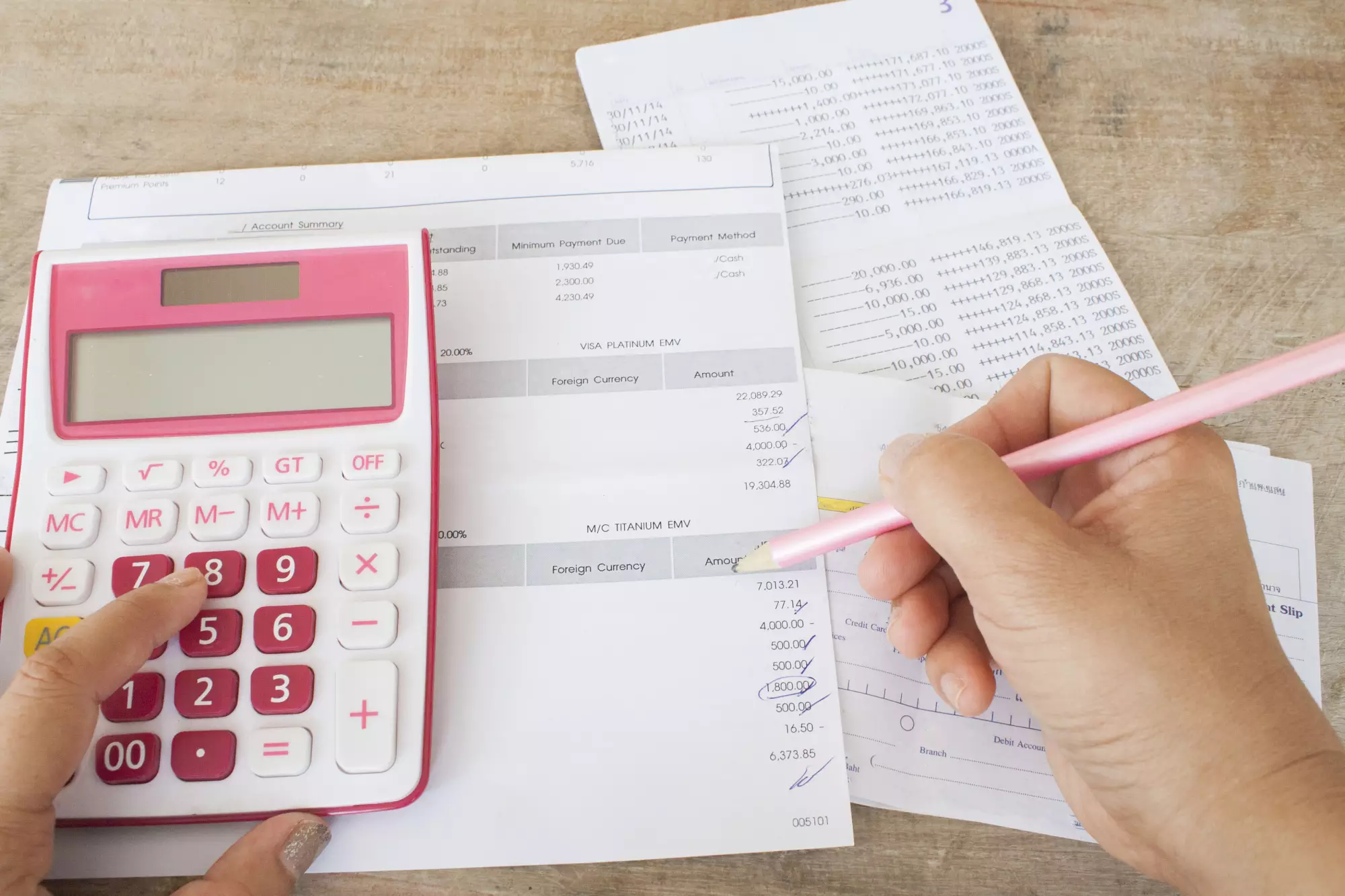 calculette rose et moins tenant un stylo au dessus de factures