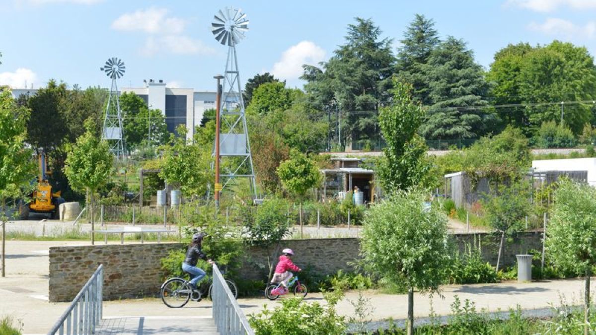 ecoquartier la bottiere chenaie nantes – Une femme et sa fille passent à vélo au milieu de la verdure