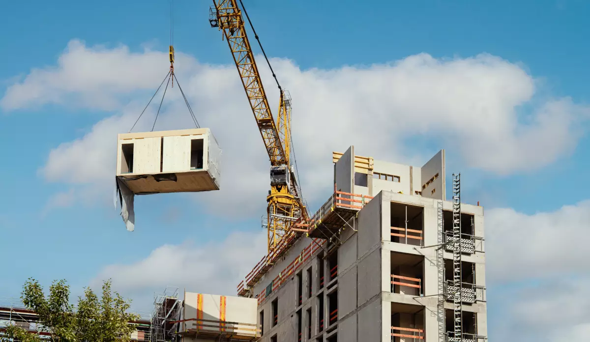 construction hors site – un module préfabriqué transporté en grue pour être placé en haut d’un bâtiment