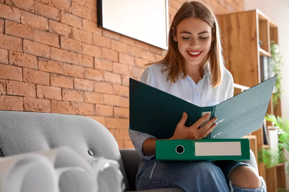 une jeune femme sourit devant un classeur ouvert