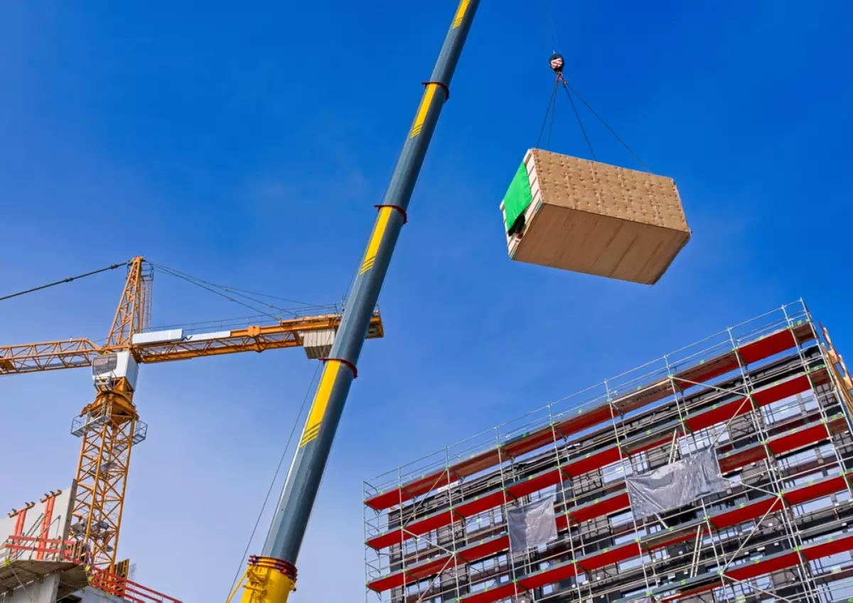 construction hors site – un module en bois transporté en grue pour être placé sur un immeuble